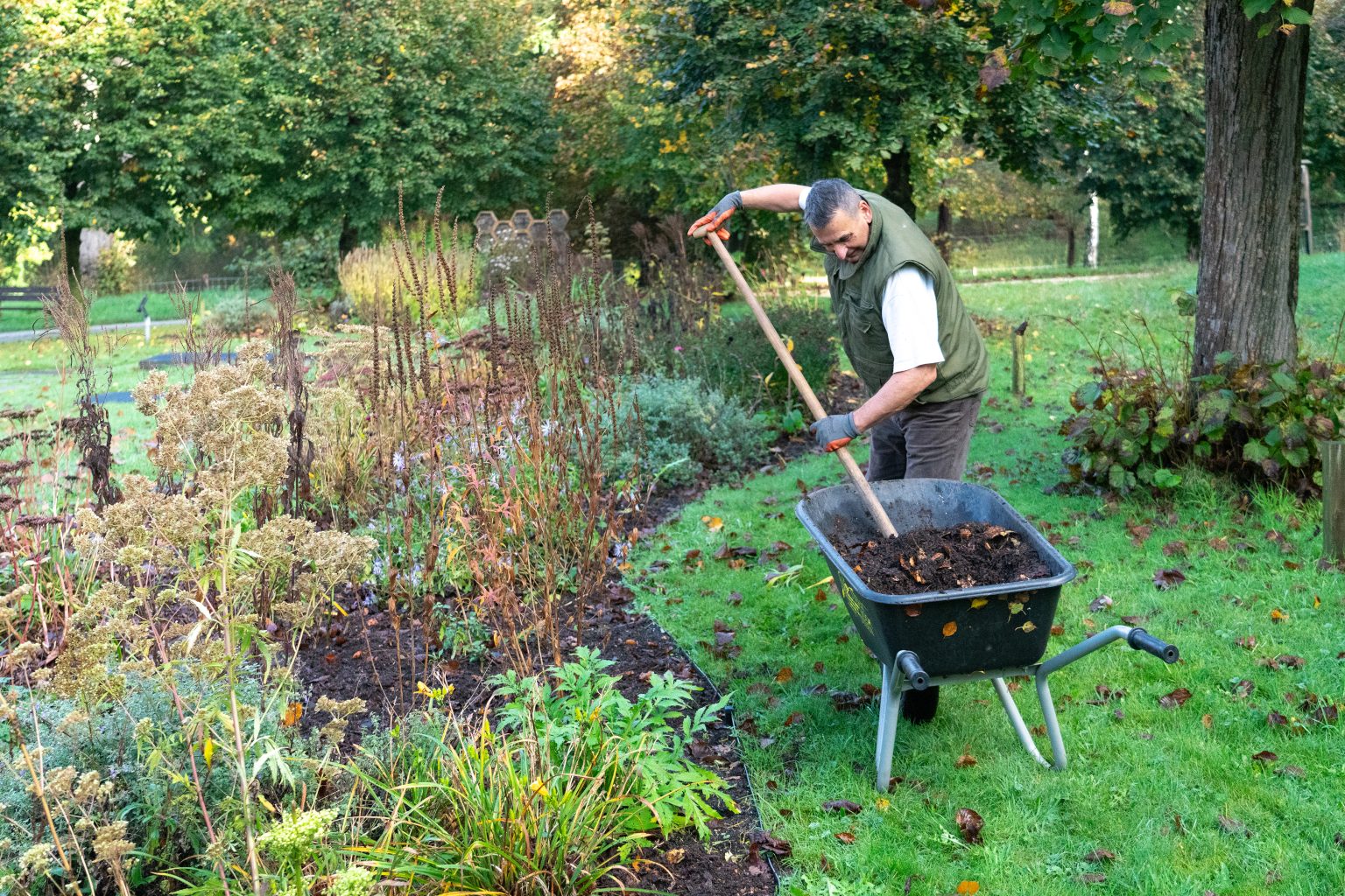 compost aanbrengen in een border door vrijwilliger van het kerkje
